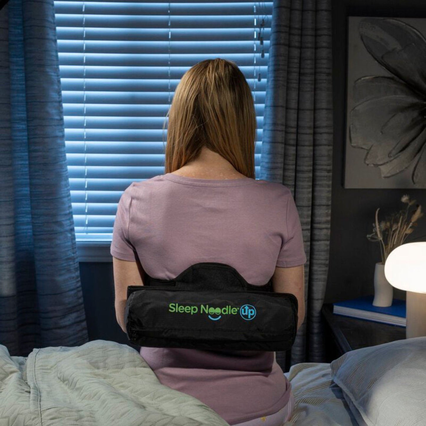 Person wearing a back brace labeled 'Sleep Needle' in a bedroom setting.