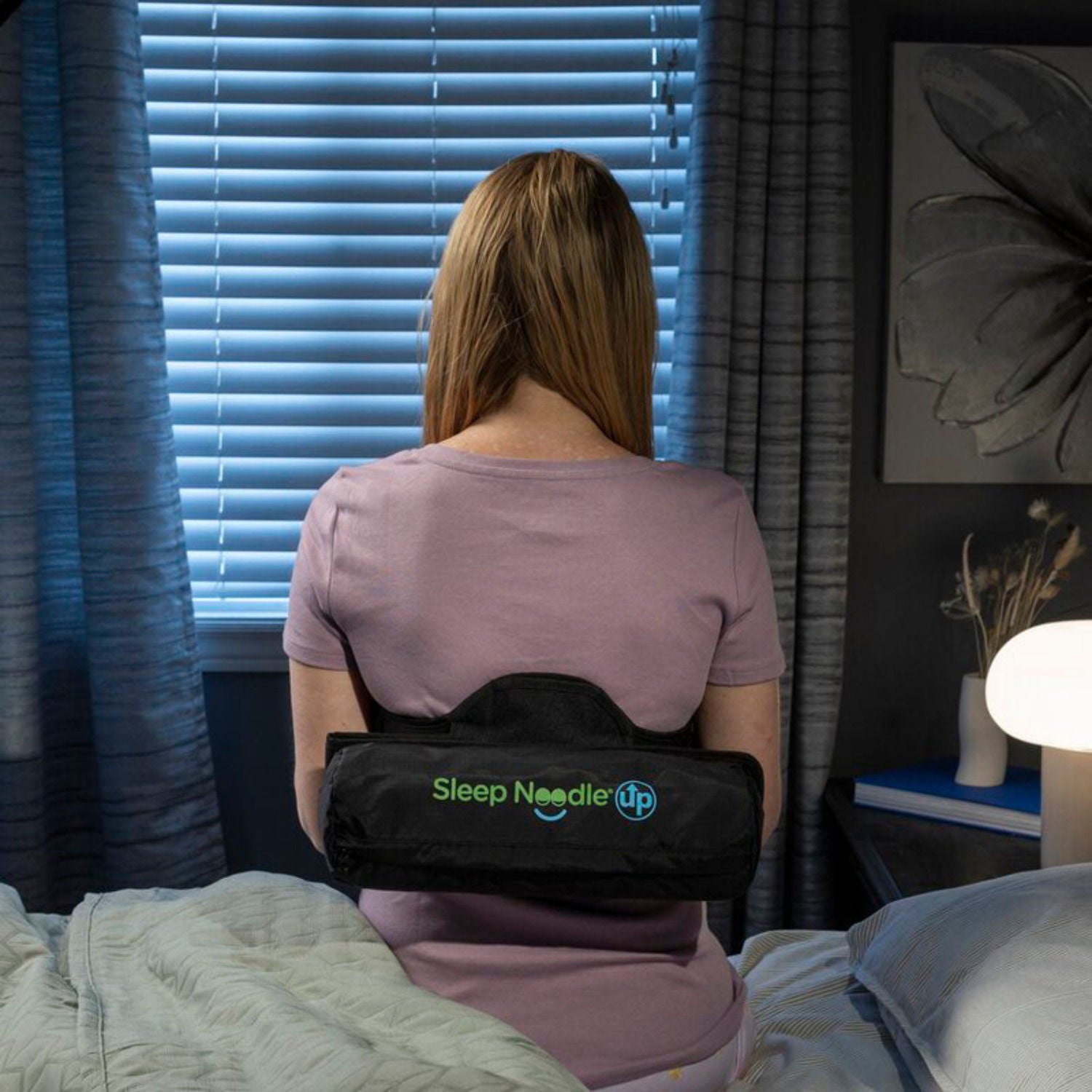 Person wearing a back brace labeled 'Sleep Needle' in a bedroom setting.